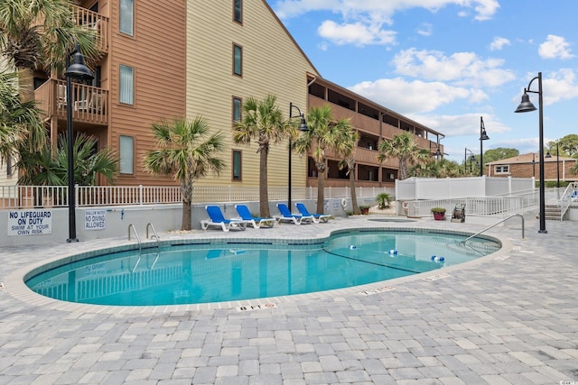 community pool with a patio and fence