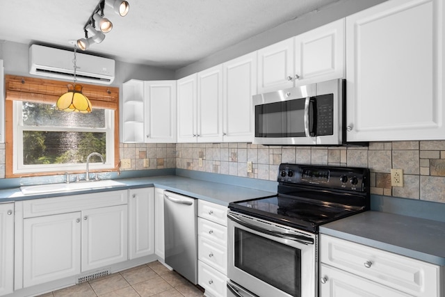 kitchen featuring pendant lighting, light tile patterned flooring, an AC wall unit, white cabinetry, and stainless steel appliances