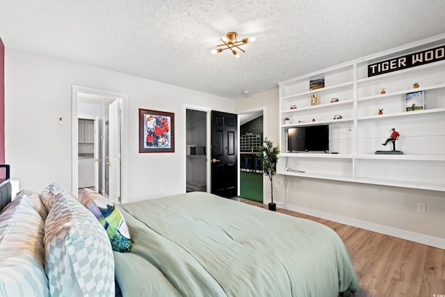 bedroom with wood-type flooring, a textured ceiling, and an inviting chandelier