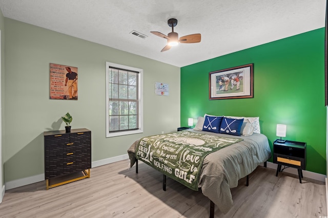 bedroom with ceiling fan, a textured ceiling, and light hardwood / wood-style flooring