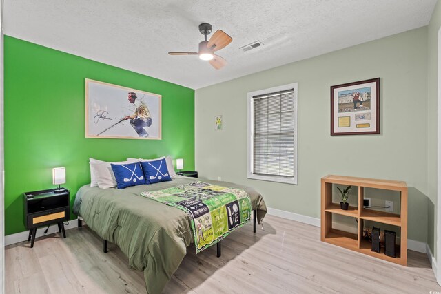 bedroom with light wood-type flooring, ceiling fan, and a textured ceiling