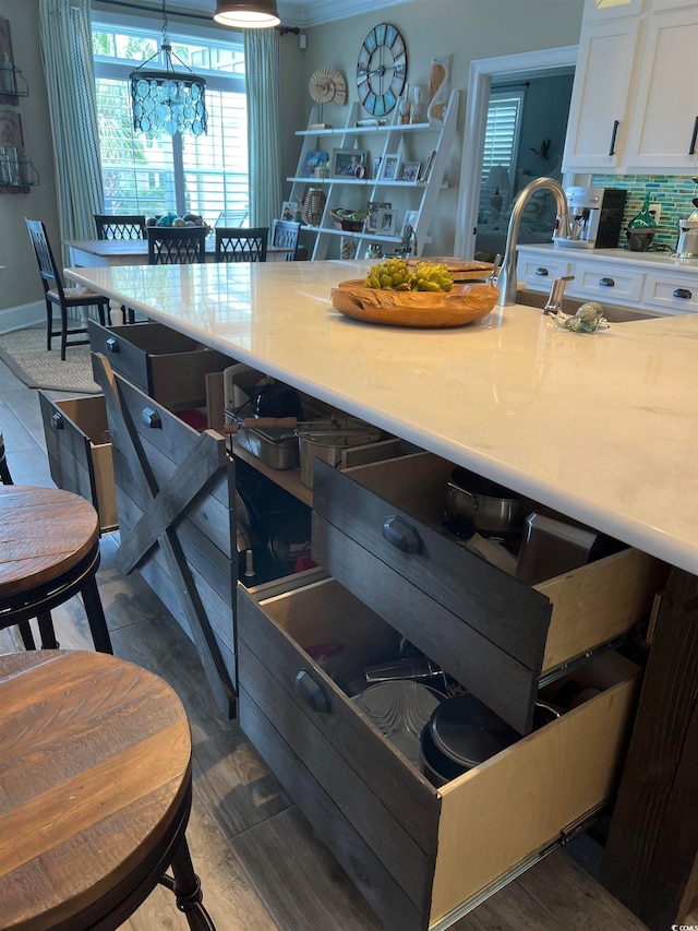 interior space featuring backsplash, white cabinetry, and a chandelier