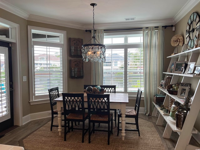 dining room with wood-type flooring, ornamental molding, and a healthy amount of sunlight