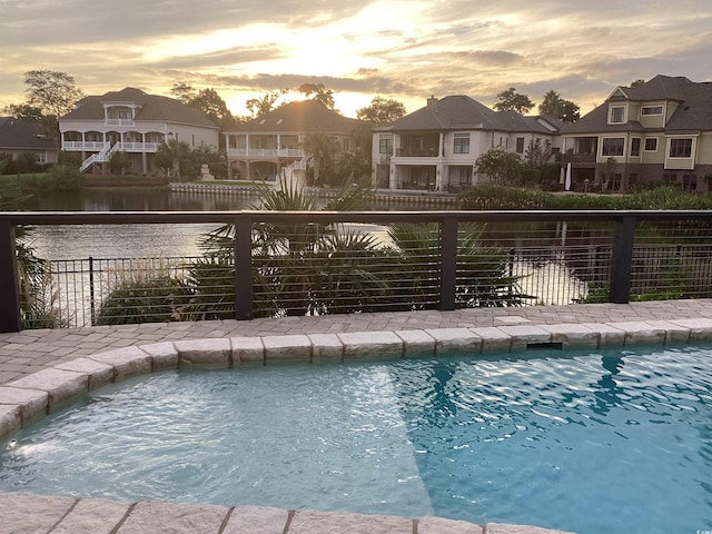 pool at dusk featuring a water view