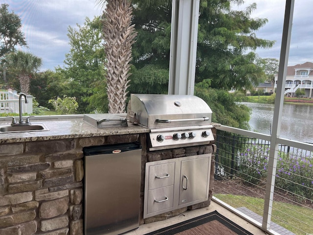 view of patio / terrace with sink, a grill, a water view, and exterior kitchen