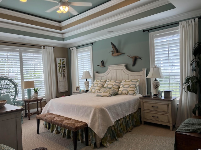 bedroom featuring ceiling fan, light colored carpet, a raised ceiling, and ornamental molding