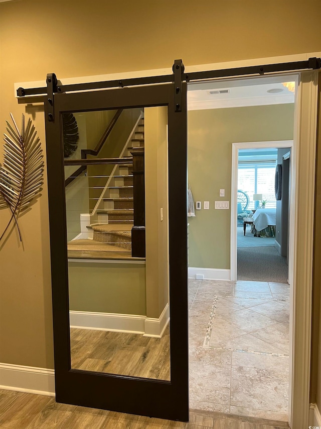 stairway with a barn door and wood-type flooring