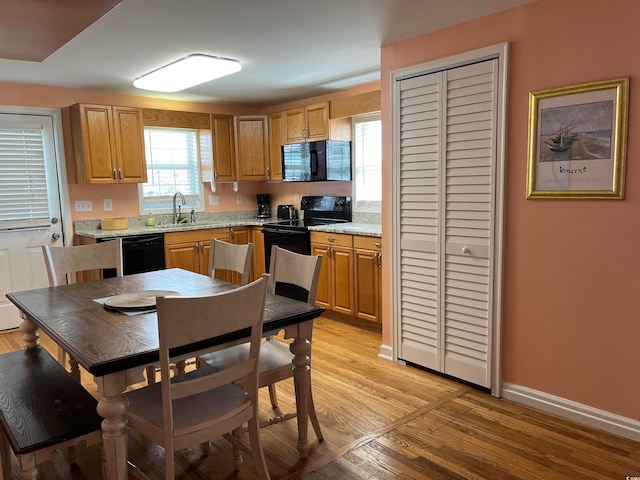 kitchen with light wood-type flooring, black appliances, and sink