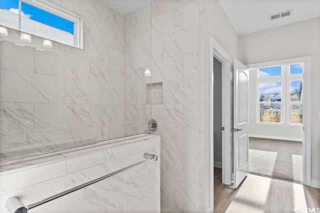 bathroom featuring hardwood / wood-style flooring and tiled shower