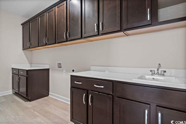 washroom with sink, cabinets, washer hookup, hookup for an electric dryer, and light wood-type flooring