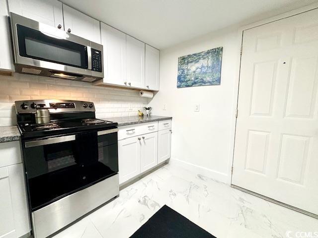 kitchen featuring dark stone countertops, backsplash, white cabinets, and appliances with stainless steel finishes