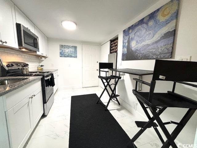 6850 Blue Heron Blvd Unit 106, Myrtle Beach, SC 29588 - kitchen featuring stainless steel appliances, dark stone countertops, white cabinets, and backsplash