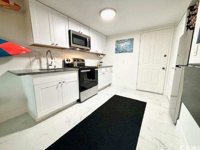 kitchen with stainless steel appliances, white cabinetry, sink, and backsplash