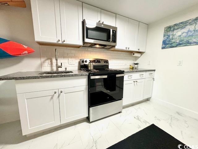 kitchen with tasteful backsplash, white cabinetry, sink, dark stone countertops, and stainless steel appliances