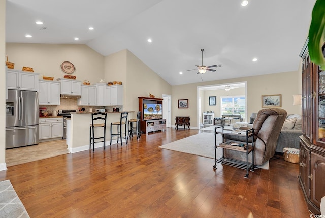 living room featuring baseboards, a ceiling fan, recessed lighting, wood finished floors, and high vaulted ceiling