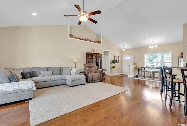 living room with baseboards, recessed lighting, wood finished floors, ceiling fan with notable chandelier, and high vaulted ceiling