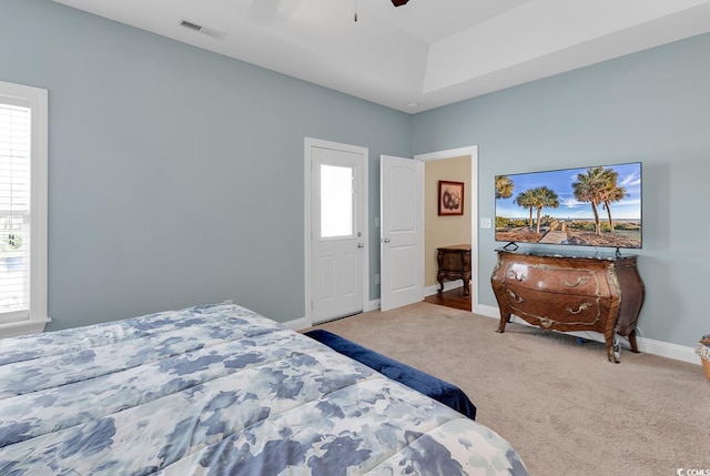 carpeted bedroom featuring visible vents, baseboards, multiple windows, and ceiling fan