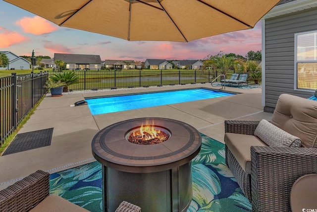 pool at dusk featuring a fenced in pool, a patio, a residential view, and a fenced backyard