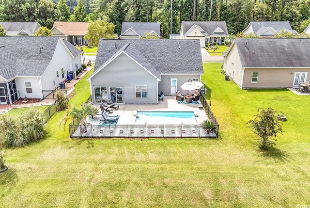 back of property with a fenced in pool, a patio area, a yard, fence, and a shingled roof
