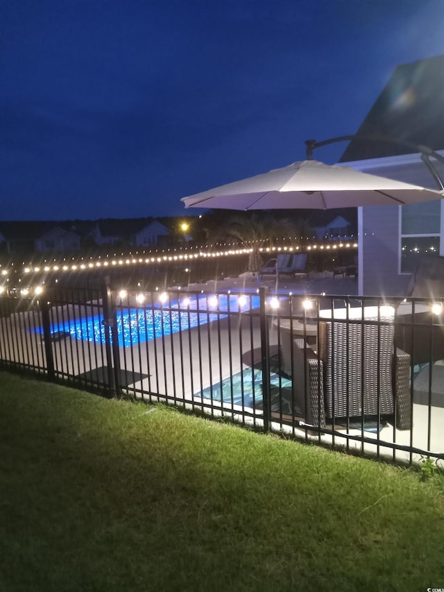 pool at night with a fenced in pool and fence