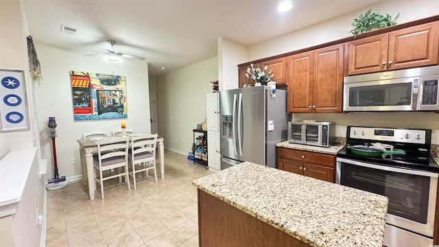 kitchen with ceiling fan, light stone countertops, stainless steel appliances, and light tile patterned floors