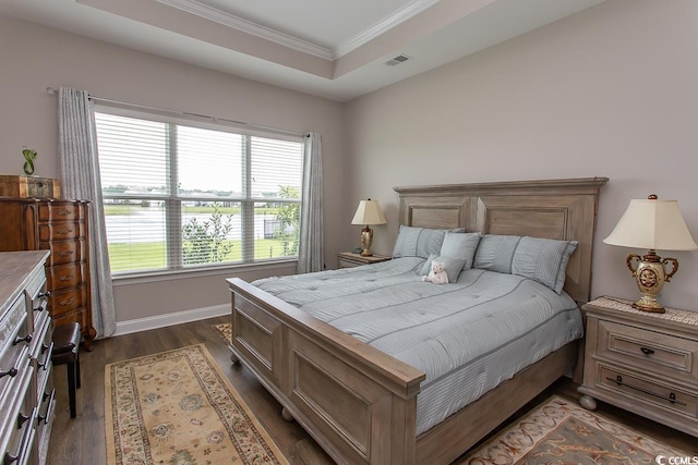 bedroom with a raised ceiling, dark hardwood / wood-style floors, and crown molding