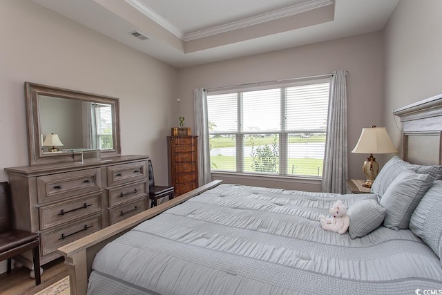 bedroom featuring light wood-type flooring, crown molding, and a tray ceiling