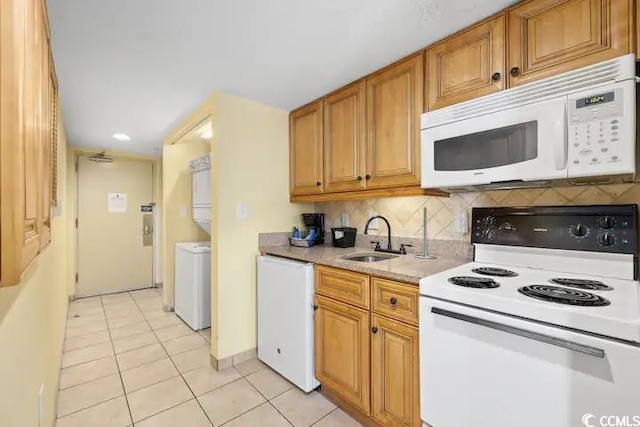 kitchen featuring backsplash, washer / dryer, sink, light tile patterned flooring, and white appliances