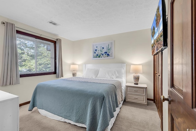 bedroom with light colored carpet and a textured ceiling