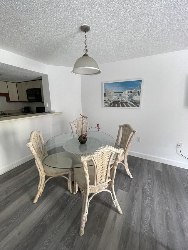 dining space with a textured ceiling and dark hardwood / wood-style flooring