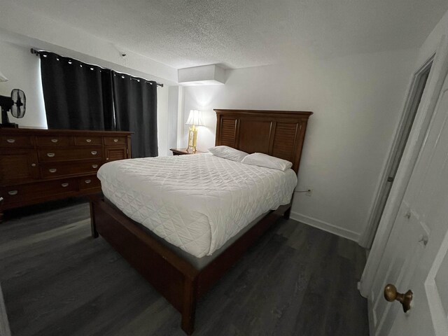 bedroom with a textured ceiling and dark hardwood / wood-style floors