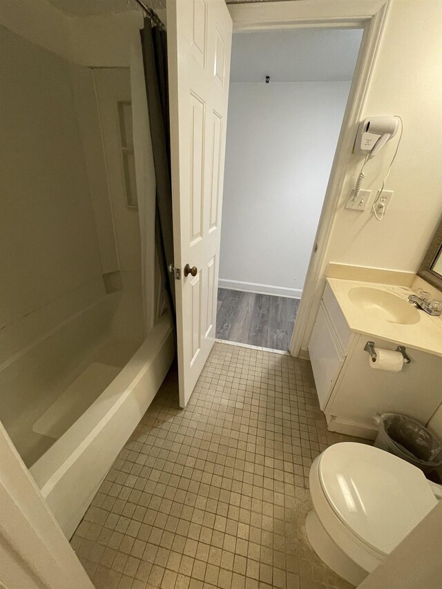 full bathroom featuring hardwood / wood-style flooring, shower / bath combination with curtain, toilet, and vanity