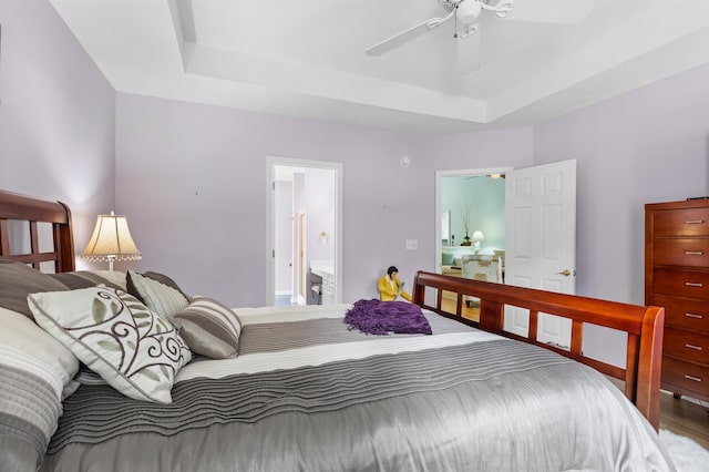 bedroom with a tray ceiling, ceiling fan, and ensuite bathroom