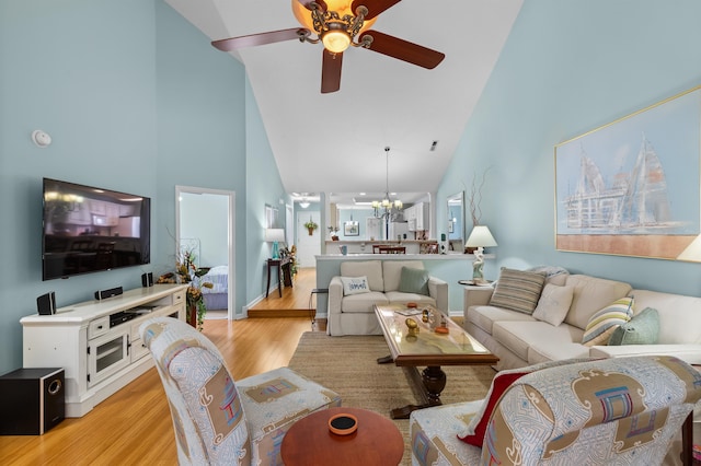 living room with light hardwood / wood-style flooring, high vaulted ceiling, and ceiling fan with notable chandelier