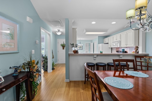 dining space with light hardwood / wood-style floors and an inviting chandelier