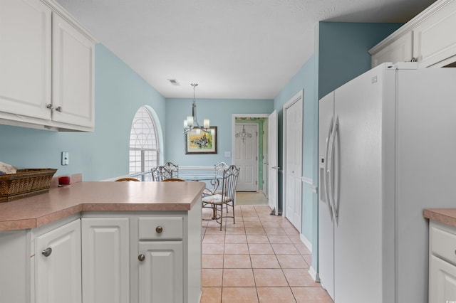 kitchen with light tile patterned floors, white fridge with ice dispenser, kitchen peninsula, and white cabinets