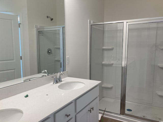 bathroom featuring double vanity, a stall shower, and a sink