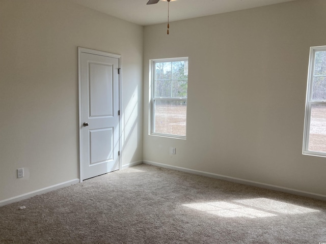 empty room with carpet flooring, a ceiling fan, and baseboards