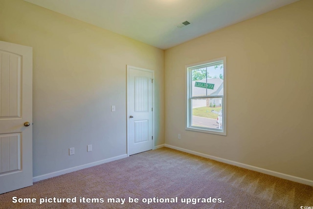 spare room featuring carpet floors, visible vents, and baseboards