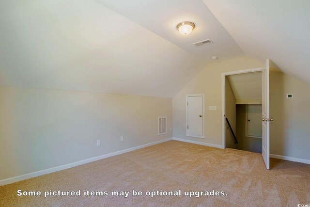 additional living space featuring vaulted ceiling and light colored carpet