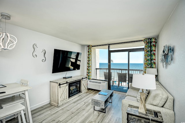 living room with a wall unit AC, a notable chandelier, and light hardwood / wood-style floors