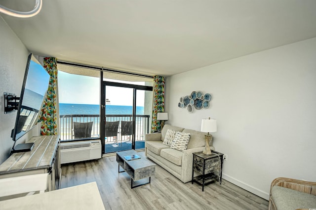 living room with a wall mounted AC, a water view, and hardwood / wood-style floors