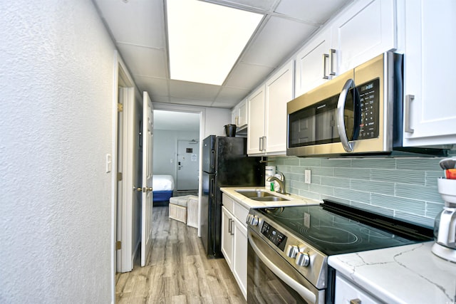 kitchen featuring light hardwood / wood-style flooring, sink, decorative backsplash, appliances with stainless steel finishes, and white cabinets