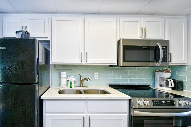 kitchen featuring white cabinets, light stone counters, stainless steel appliances, sink, and tasteful backsplash