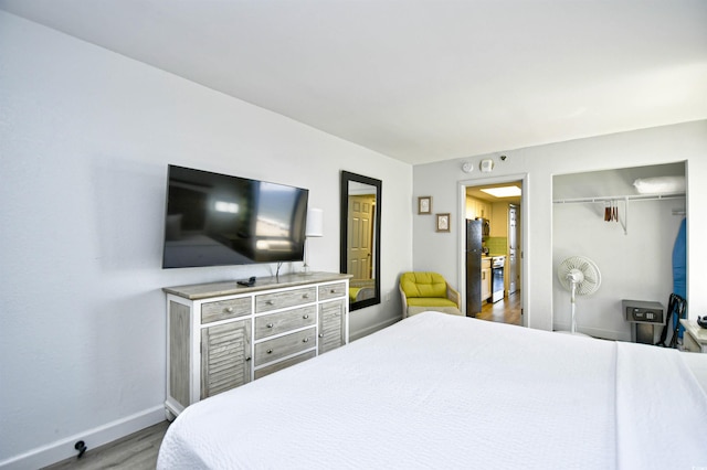 bedroom featuring a closet, wood-type flooring, and black fridge