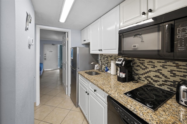 kitchen featuring light stone counters, backsplash, white cabinets, a sink, and black appliances