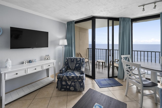 living room featuring a textured ceiling, light tile patterned floors, a water view, a wall of windows, and rail lighting