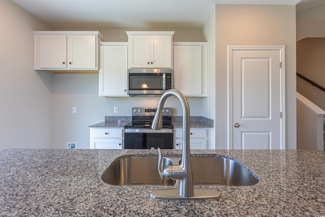 kitchen with dark stone countertops, white cabinetry, sink, and appliances with stainless steel finishes