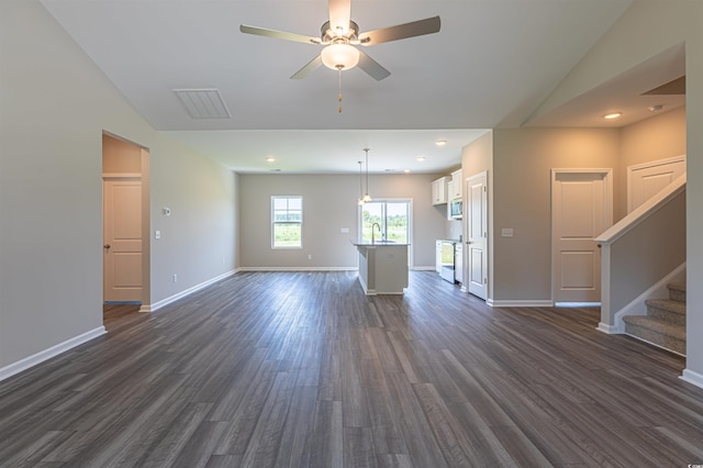 unfurnished living room featuring ceiling fan, sink, dark wood-type flooring, and vaulted ceiling