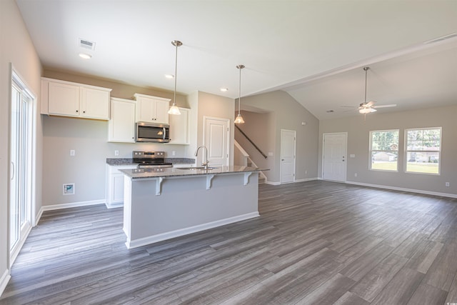 kitchen featuring white cabinetry, stainless steel appliances, a kitchen island with sink, and a breakfast bar area